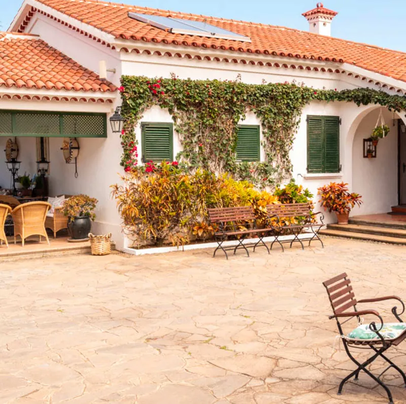 Fachada blanca de la casa con buganvillas y patio